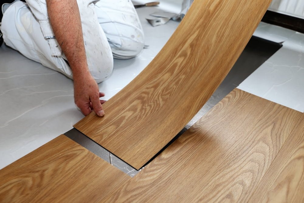 A man is installing a wooden floor in a room.